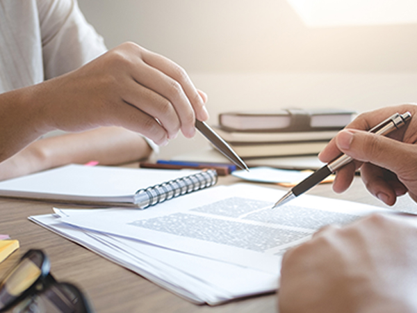 two people pointing at a printed case study reviewing